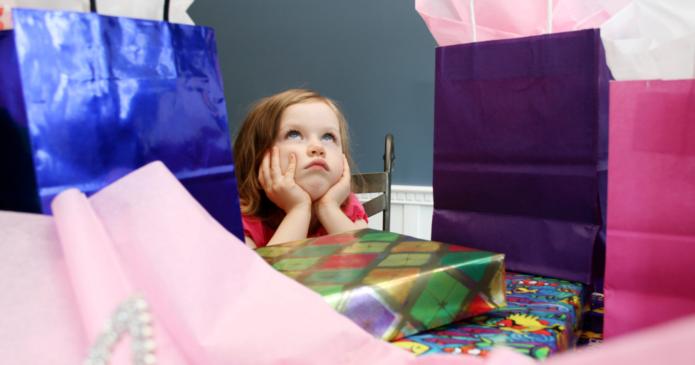 Jól szeretni. Kislány csalódottan fekszik az ajándékok között.