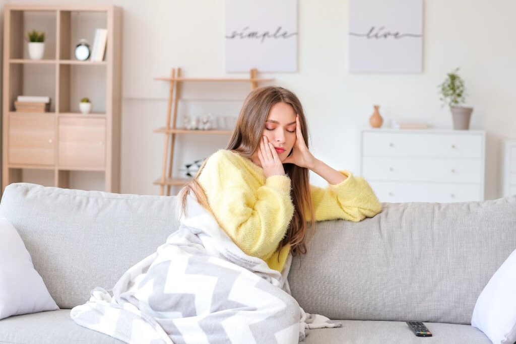 krónikus fájdalom - nő fogja a fejét a kanapén